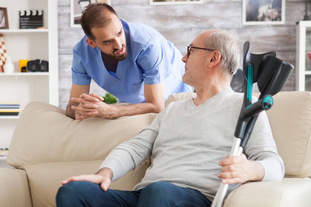 Aide speaks with patient sitting on a couch Aide speaks with patient sitting on a couch