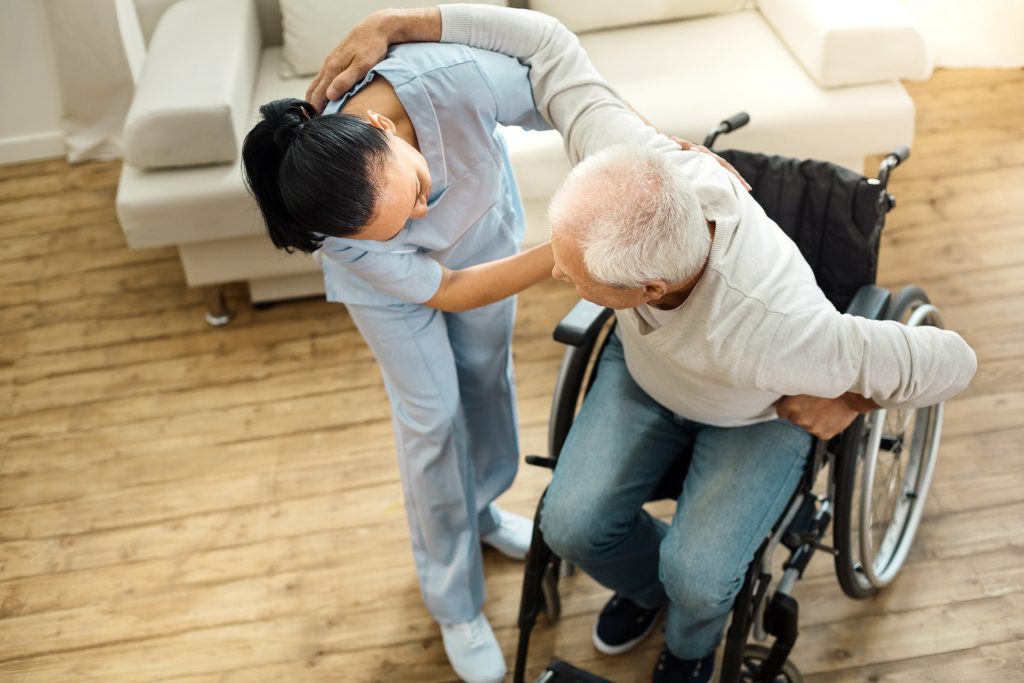 Occupational therapist helps a patient out of wheelchair at home Occupational therapist helps a patient out of wheelchair at home