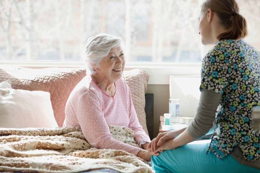 homecare nurse and elderly patient homecare nurse talks with and elderly patient who is sitting in bed