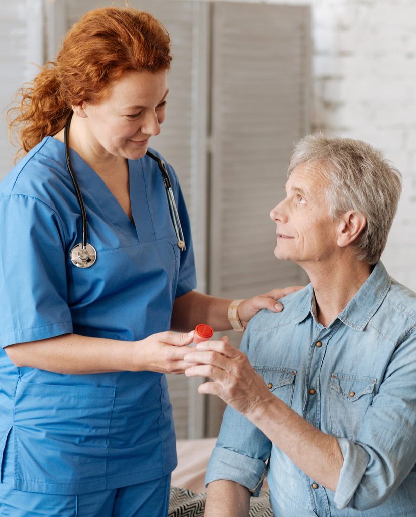 In-home skilled nurse hands medication to a patient In-home skilled nurse hands medication to a patient